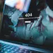 MacBook Pro screen displaying a 404 error page with a blurred background and reflections on the screen.