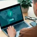 Person using laptop with VPN protection interface showing shield and world map on screen.