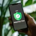 Hand holding smartphone showing VPN protected screen with green shield and checkmark symbol