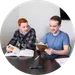 Two students collaborating at a table with textbooks and a tablet, engaging in a productive study session.