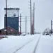 a snowy road with power lines and buildings on either side of it