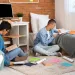 Two students studying with books and notebooks while sitting on the floor in a cozy bedroom