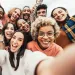 Diverse group of happy young adults taking a cheerful selfie outdoors, smiling and enjoying together.