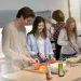 a group of people standing around a table with food on it