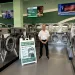 Man standing in modern laundromat with rows of washers and a wash and fold service sign