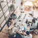 Overhead view of diverse team collaborating around a table covered with laptops, papers, and coffee in modern office