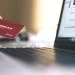 Hand holding a credit card near a laptop screen displaying an online shopping website for secure payment