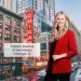 Smiling woman in red blazer standing in Chicago downtown with iconic Chicago Theatre sign and city buildings