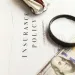 Cyber insurance policy document with a toy car, magnifying glass, and US dollar bills on a white surface