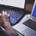vCSO - virtual chief security officer-typing on a Dell laptop keyboard next to a MacBook Air on a white surface.