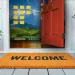 Open red door with welcome mat and potted plants revealing a desktop screen with folders and mountain wallpaper inside home.
