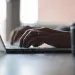 Close-up of hands typing on a laptop keyboard with natural light in the background
