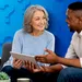 Smiling mature woman and man discussing while holding a digital tablet with question marks on blue background