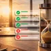 Hourglass and laptop on desk with checklist icons symbolizing time management and task completion at sunset.