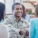 Smiling soldier in camouflage shaking hands with a woman in a friendly indoor setting.