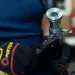 Worker wearing gloves measures metal pipe diameter with digital caliper in workshop setting.