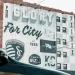 Sporting Kansas City mural on brick building celebrating soccer achievements and city pride with trophies and logos.