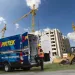 Pirtek mobile hose service van with technician on construction site under blue sky and cranes.