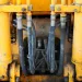 Close-up of yellow heavy machinery hydraulic system with hoses and metal connectors showing wear and dirt