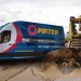 Pirtek mobile hose service van parked next to a bulldozer in a sandy construction site under cloudy sky.