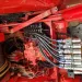 Close-up of hydraulic system with multiple hoses and metal fittings on industrial red machinery.