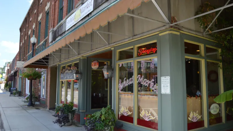 Historic downtown street with brick buildings and a cafe named Sunflower Market on the corner under an awning.