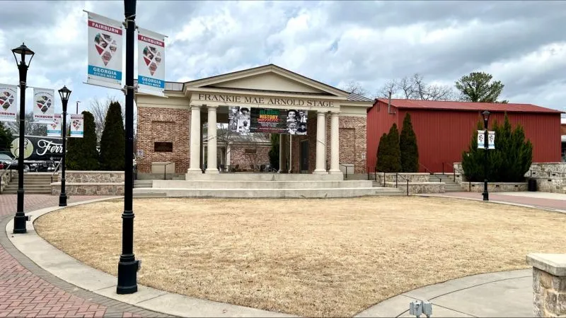 Outdoor view of Frankie Mae Arnold Stage with banners and cloudy sky in a public park in Georgia