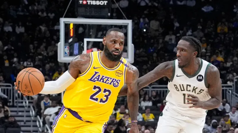 Lakers player dribbling basketball past Bucks defender during intense NBA game on court
