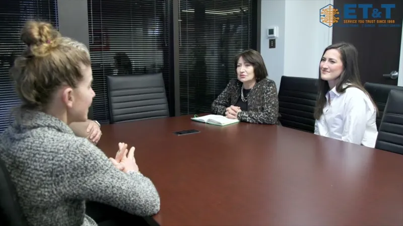 Three women having a professional meeting in a modern office conference room at a wooden table.
