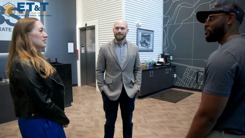 Three professionals having a conversation in a modern office lobby with geometric wall art and hardwood flooring.
