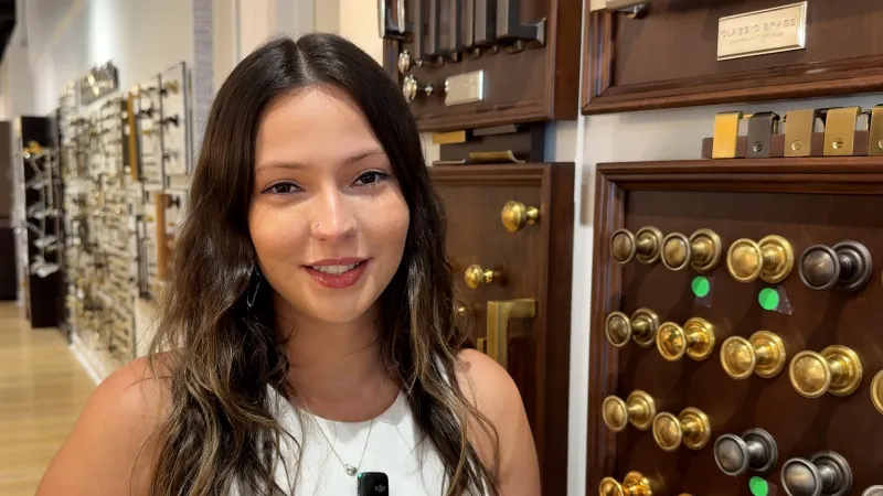 Woman smiling in a hardware store aisle with displays of decorative drawer knobs and handles.