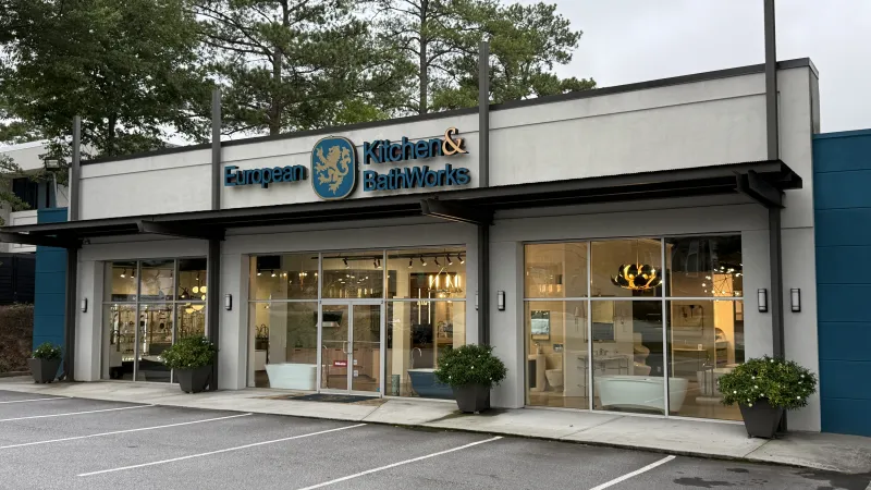 European Kitchen & Bath Works storefront with large windows and potted plants in a quiet parking lot