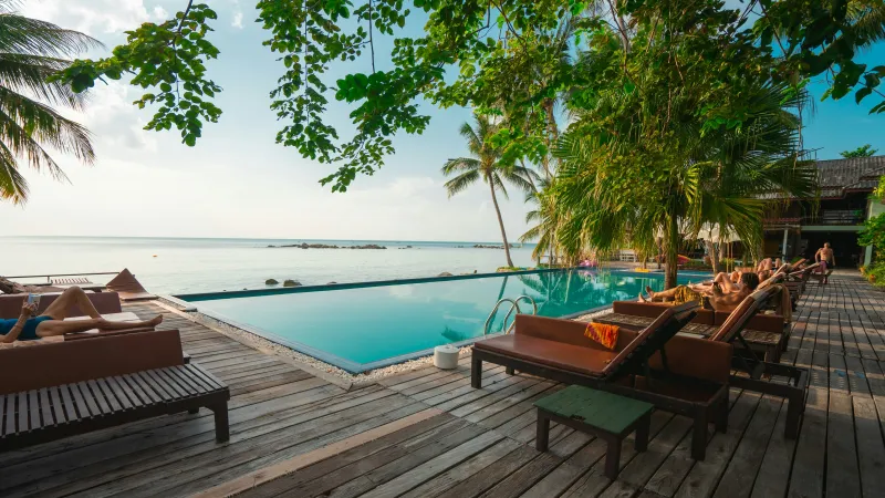 a deck with chairs and tables by a pool