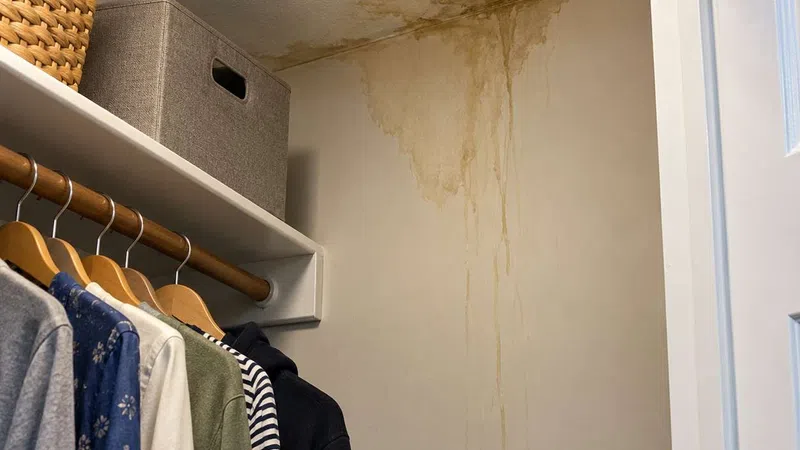 Large water damage stain on closet ceiling and wall in closet with water leak