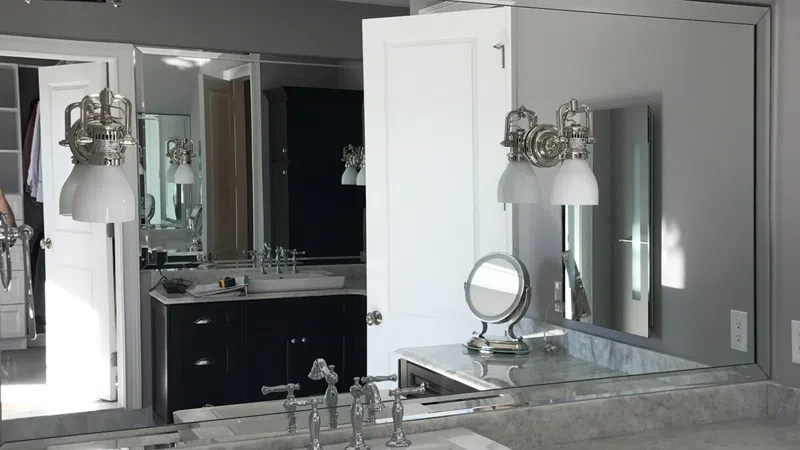 Modern bathroom with marble countertop, white sink, large mirrors, and wall-mounted light fixtures.