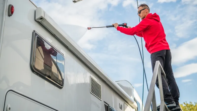 a man on a ladder performing RV maintenance