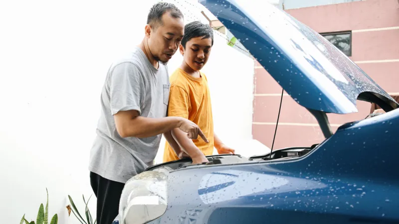 A man and son looking under the hood of a car