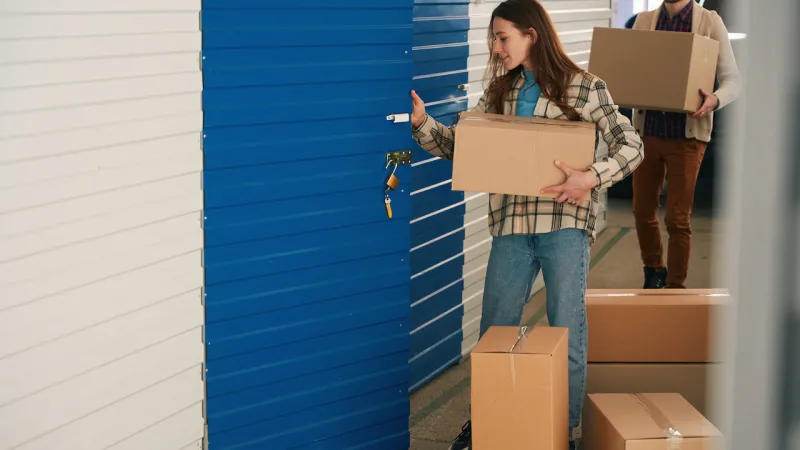 people carry boxes into their storage unit