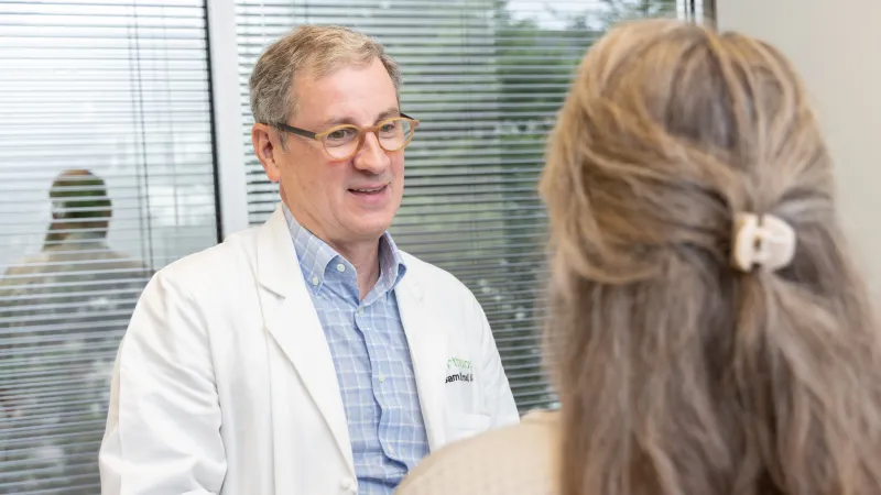 A doctor in a white coat engages with a patient during a consultation in a bright office.