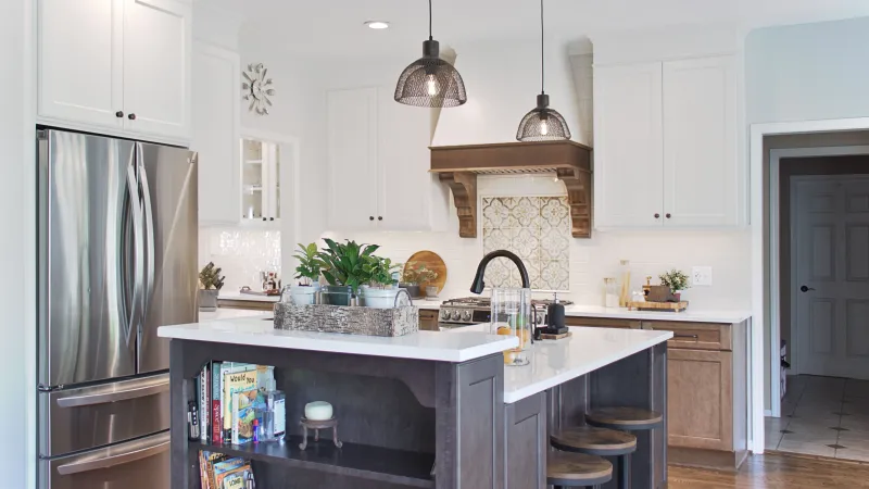 a kitchen with a two-tone hood and three colors of cabinets