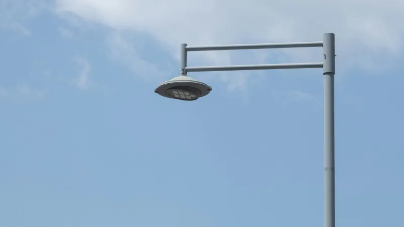 Modern street lamp with LED lights under a partly cloudy blue sky during daytime.
