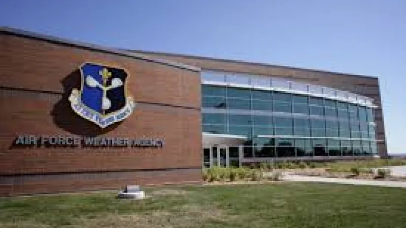 Modern Air Force Weather Agency building with large glass windows and emblem on brick wall under clear sky.