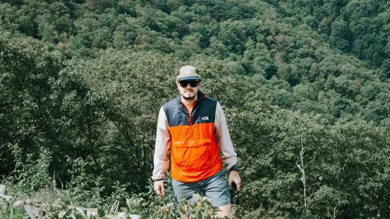 a man standing next to a forest