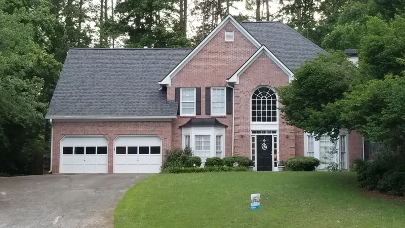 a large brick building with green grass in front of a house
