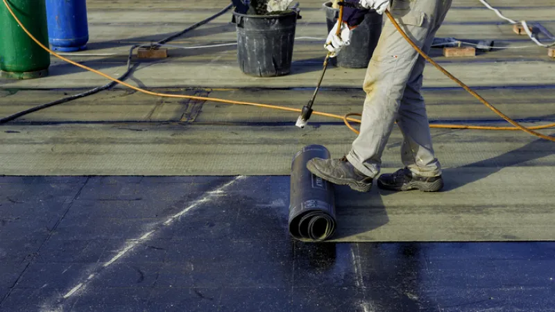 man installing flat roofing material