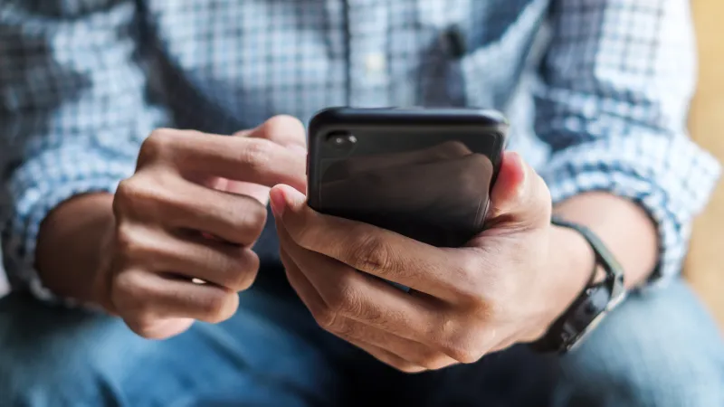 A person using a smartphone in a cozy indoor setting, focused on the screen.