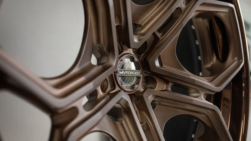 Close-up of a bronze MV Forged custom forged alloy wheel with intricate spoke design and detailed center cap.