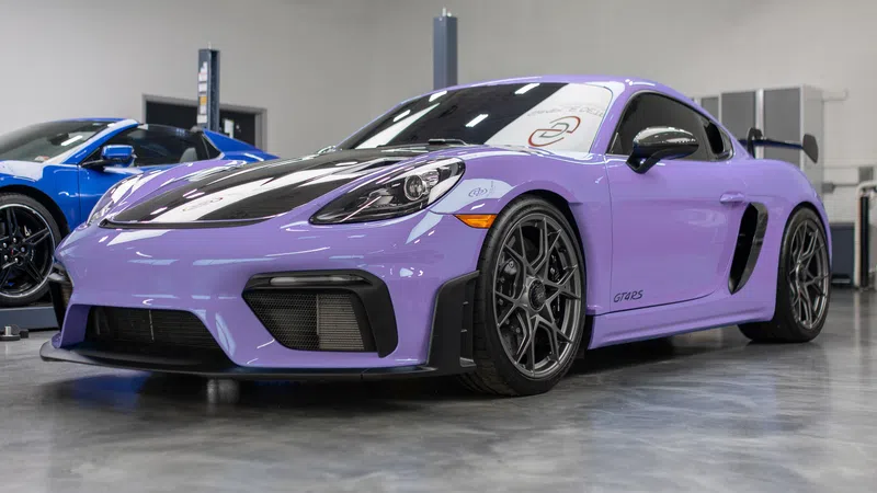 Purple Porsche GT4 RS sports car with black accents parked indoors on polished concrete floor.