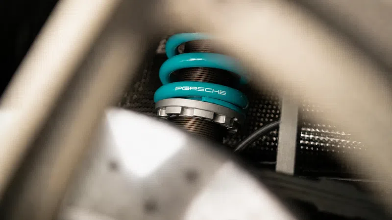 Close-up of a turquoise Porsche suspension coil spring inside a car's mechanical system.