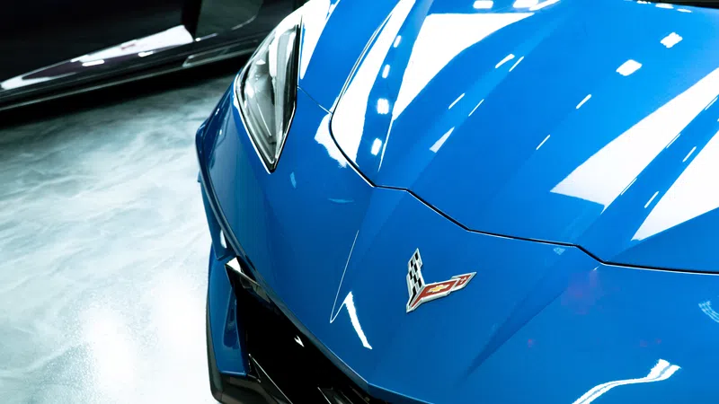 Close-up of a blue sports car front with sleek headlights and Corvette badge on display.
